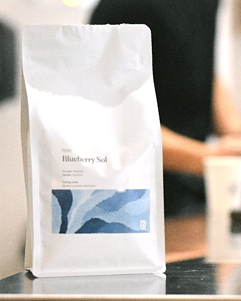 Blueberry Sol pose på disken mens baristaen arbejder i Piccolo Espressobar